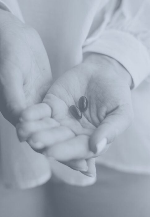 Hands holding two medication pills